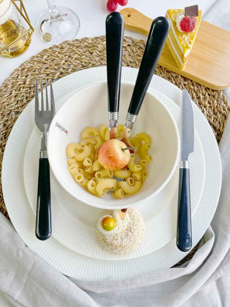 ชุดช้อนส้อมด้ามดำจัดวางบนโต๊ะอาหารสีขาว